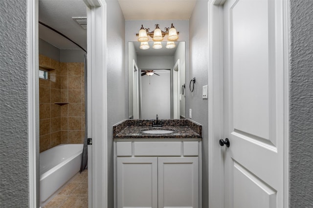 bathroom with tile patterned flooring, a textured wall, shower / bath combination, vanity, and ceiling fan with notable chandelier