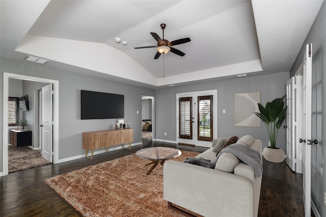 living room featuring vaulted ceiling, ceiling fan, visible vents, baseboards, and dark wood-style floors