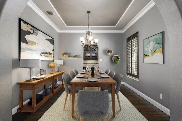 dining space featuring a tray ceiling, wood finished floors, visible vents, baseboards, and a notable chandelier