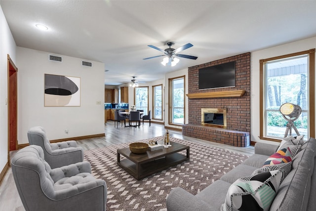 516 Wild Wood Dr, Decatur, TX 76234 - living room with light wood finished floors, a ceiling fan, and a brick fireplace