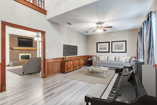516 Wild Wood Dr, Decatur, TX 76234 - living room featuring a ceiling fan, light wood finished floors, wainscoting, and a fireplace