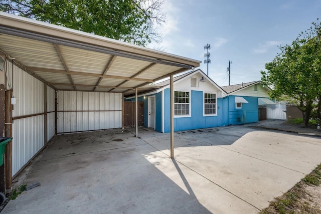 exterior space with driveway, a carport, and fence
