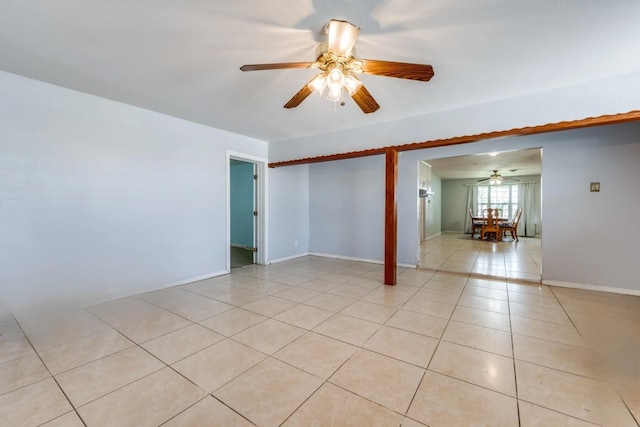 empty room with baseboards, ceiling fan, and light tile patterned floors