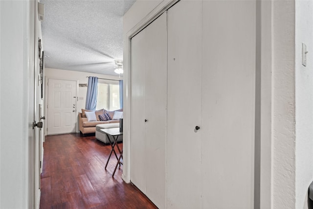 corridor featuring a textured ceiling and dark wood-style floors