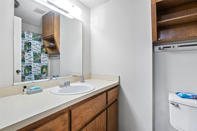 full bath with vanity, a textured ceiling, and toilet