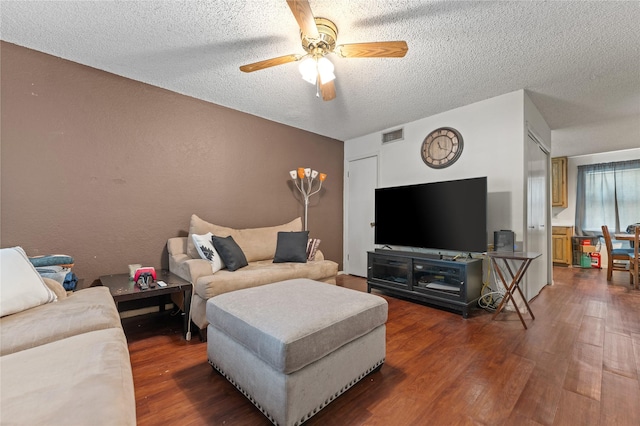 living area with visible vents, a ceiling fan, wood finished floors, and a textured ceiling