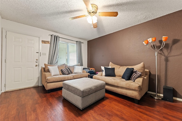 living area featuring dark wood finished floors, a textured wall, a textured ceiling, and a ceiling fan