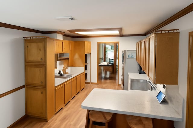 5021 Kenilworth Dr, Bossier City, LA 71112 - kitchen featuring light wood-type flooring, crown molding, light countertops, a peninsula, and a kitchen bar