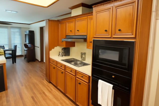 5021 Kenilworth Dr, Bossier City, LA 71112 - kitchen with black appliances, light wood-type flooring, brown cabinets, light countertops, and ornamental molding