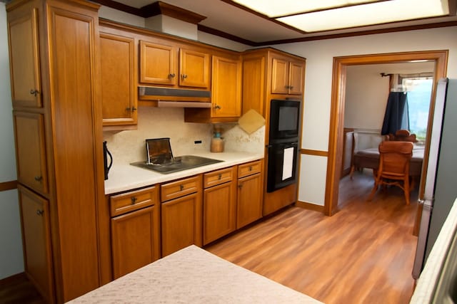 5021 Kenilworth Dr, Bossier City, LA 71112 - kitchen featuring light countertops, light wood-style flooring, brown cabinets, and decorative backsplash
