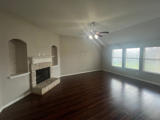 unfurnished living room featuring dark wood-style floors, vaulted ceiling, a ceiling fan, baseboards, and a fireplace