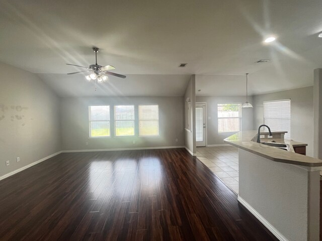 unfurnished living room with a sink, visible vents, baseboards, wood finished floors, and ceiling fan