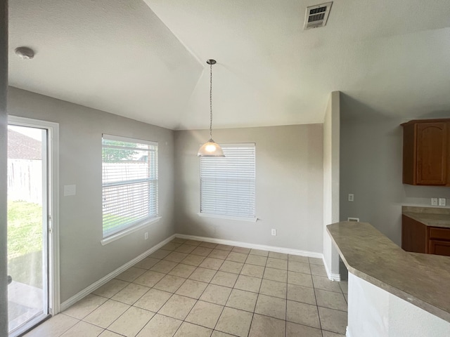 unfurnished dining area featuring baseboards, vaulted ceiling, visible vents, and light tile patterned flooring