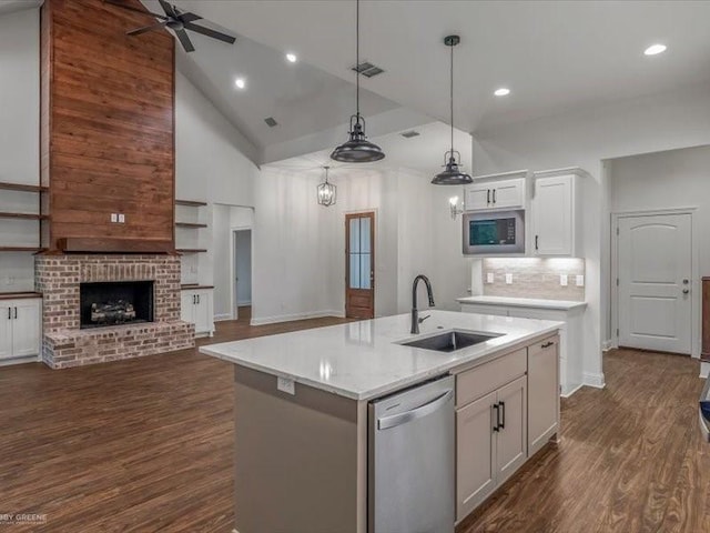 kitchen with stainless steel appliances, a sink, dark wood-style flooring, open floor plan, and high vaulted ceiling