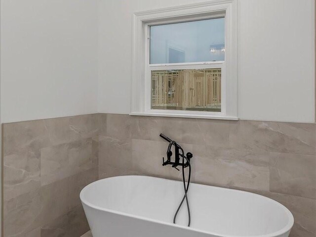 full bath featuring tile walls and a soaking tub
