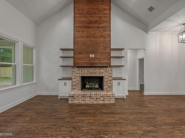 unfurnished living room featuring an inviting chandelier, baseboards, high vaulted ceiling, and dark wood-type flooring
