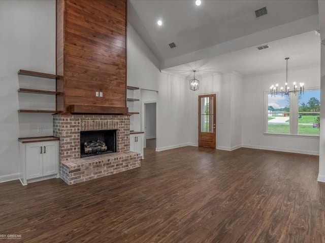 unfurnished living room featuring dark wood-type flooring, a brick fireplace, visible vents, and an inviting chandelier