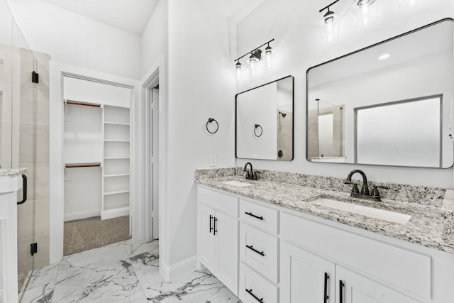 full bath with a sink, double vanity, a stall shower, a spacious closet, and marble finish floor