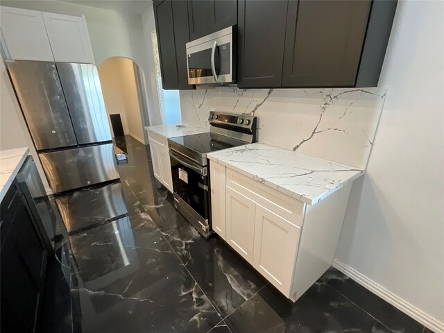 818 Rd 5607, Cleveland, TX 77327 - kitchen featuring stainless steel appliances, arched walkways, tasteful backsplash, marble finish floor, and light stone countertops