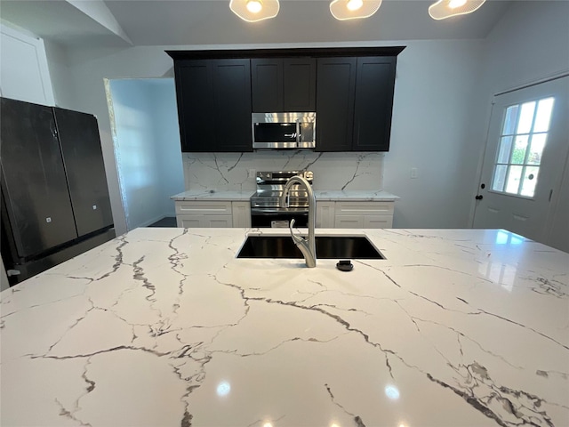 818 Rd 5607, Cleveland, TX 77327 - kitchen featuring appliances with stainless steel finishes, light stone countertops, a sink, and dark cabinetry