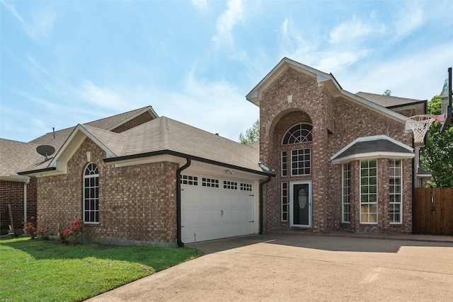 traditional home with driveway, fence, brick siding, a garage, and a front yard