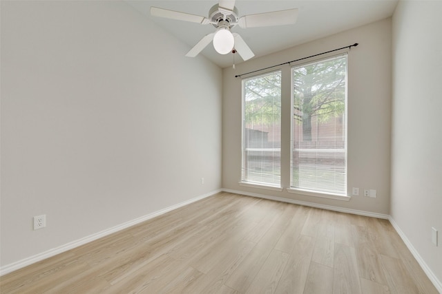 empty room with vaulted ceiling, baseboards, a ceiling fan, and light wood-style floors