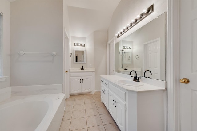 full bath featuring two vanities, tile patterned floors, a garden tub, and a sink