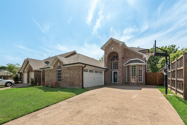 view of front of property featuring driveway, fence, brick siding, an attached garage, and a front yard