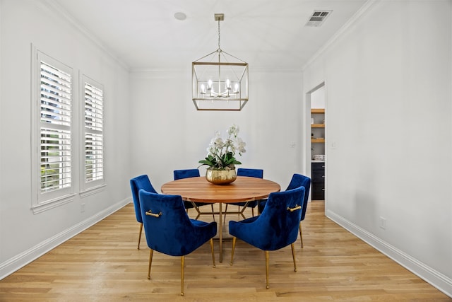 dining room featuring a notable chandelier, light wood finished floors, crown molding, and visible vents