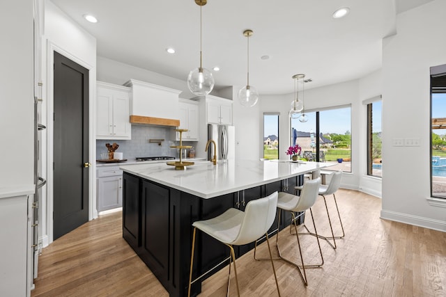 kitchen with backsplash, light wood finished floors, white cabinets, and recessed lighting