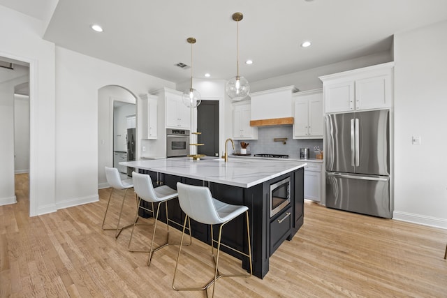 kitchen featuring stainless steel appliances, baseboards, visible vents, white cabinetry, and custom range hood