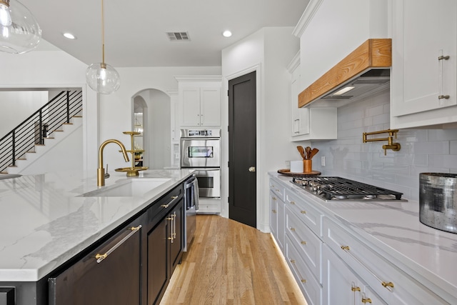 kitchen featuring stainless steel appliances, visible vents, a sink, custom exhaust hood, and white cabinetry