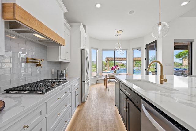 kitchen with white cabinets, stainless steel appliances, a sink, a healthy amount of sunlight, and custom exhaust hood