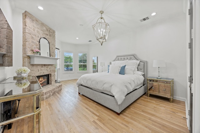 bedroom featuring light wood finished floors, baseboards, visible vents, a chandelier, and a fireplace