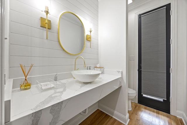bathroom featuring wooden walls, wood finished floors, toilet, and vanity