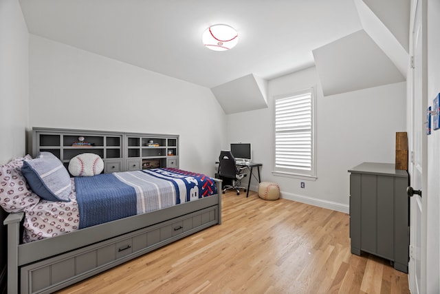 bedroom with vaulted ceiling, light wood finished floors, and baseboards