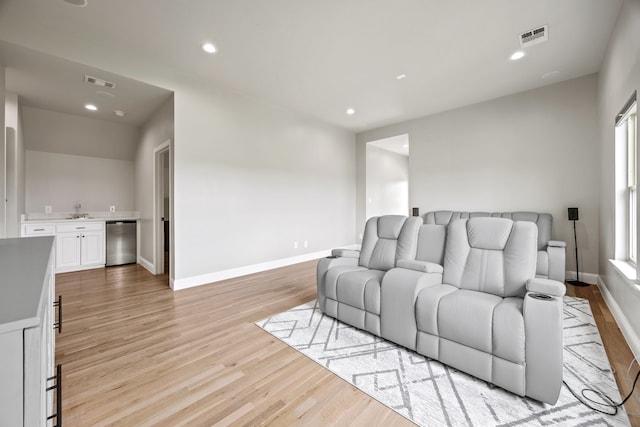 living area featuring wet bar, visible vents, and light wood finished floors