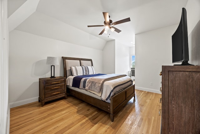 bedroom with vaulted ceiling, light wood-style flooring, a ceiling fan, and baseboards