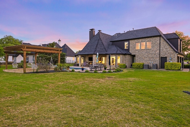 back of house at dusk featuring a pergola, central AC, fence, a yard, and a patio