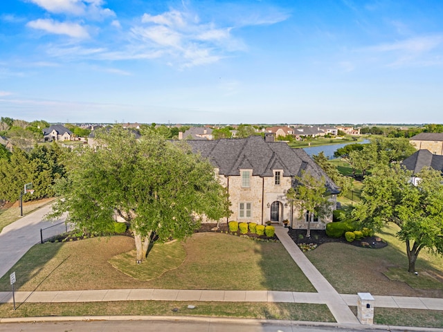 view of front of house with a front lawn, a residential view, a water view, and stone siding