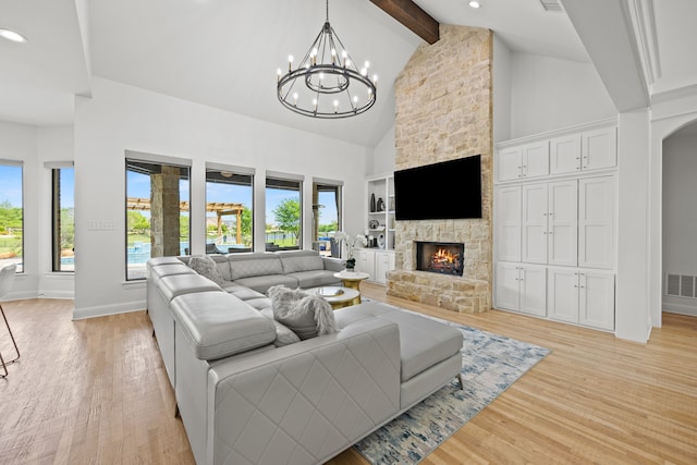living area featuring light wood-type flooring, a fireplace, a chandelier, and beamed ceiling