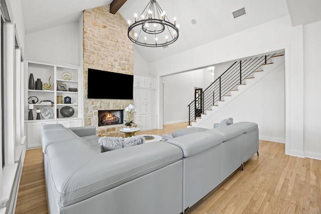 living area with light wood-style flooring, beam ceiling, visible vents, a chandelier, and stairs