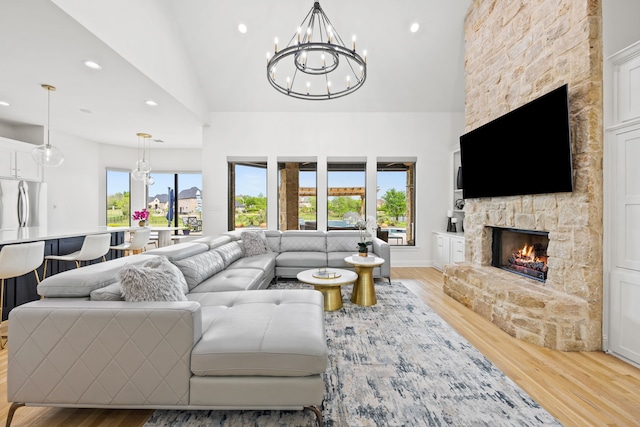 living area with light wood-style flooring, recessed lighting, a notable chandelier, and a fireplace
