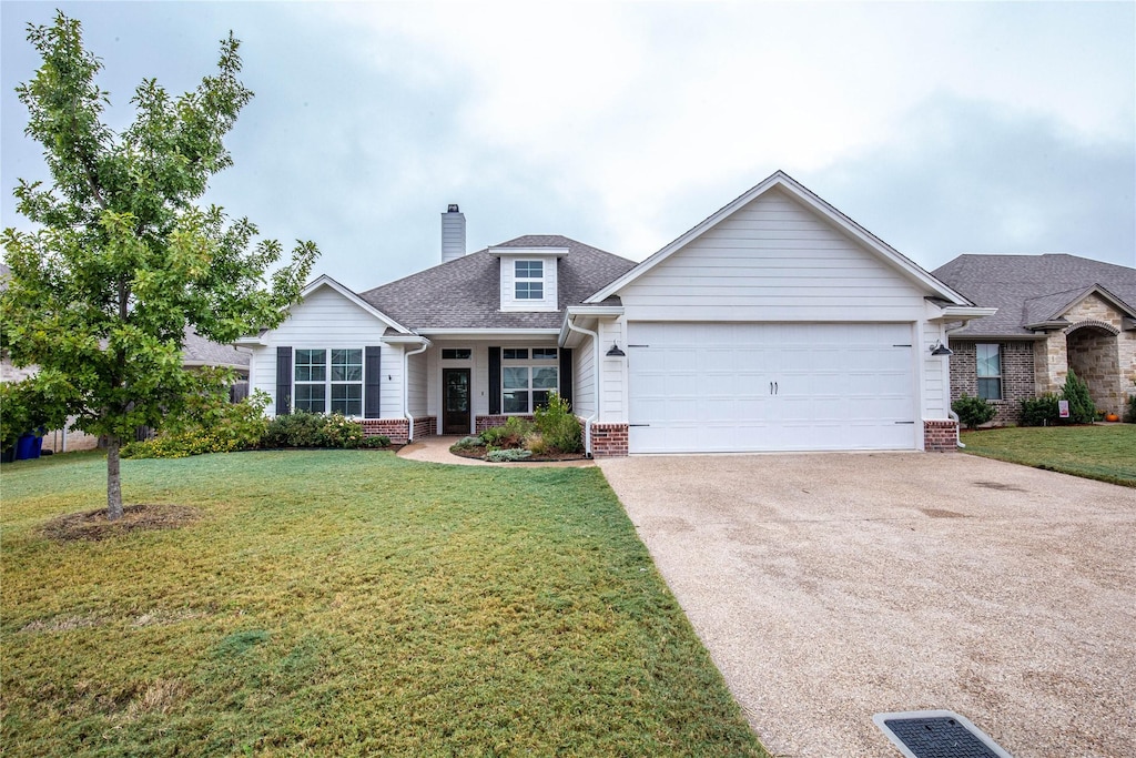 view of front of home with a chimney, concrete driveway, brick siding, a front yard, and a garage
