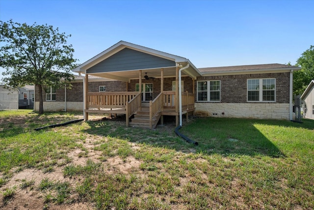 back of house featuring a wooden deck, a yard, a ceiling fan, and stone siding