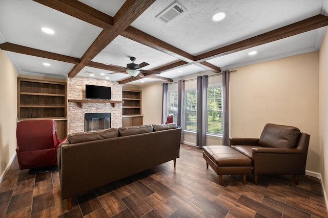 living area with baseboards, beam ceiling, a large fireplace, and visible vents