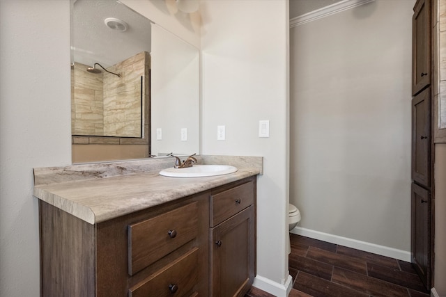 bathroom with wood finished floors, toilet, vanity, ornamental molding, and baseboards