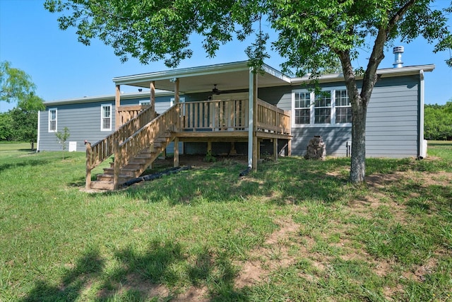 back of property with ceiling fan, stairs, and a yard