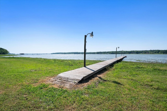 dock area with a lawn and a water view