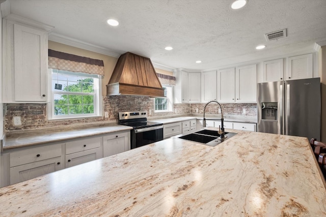 kitchen featuring plenty of natural light, custom exhaust hood, a sink, and electric range